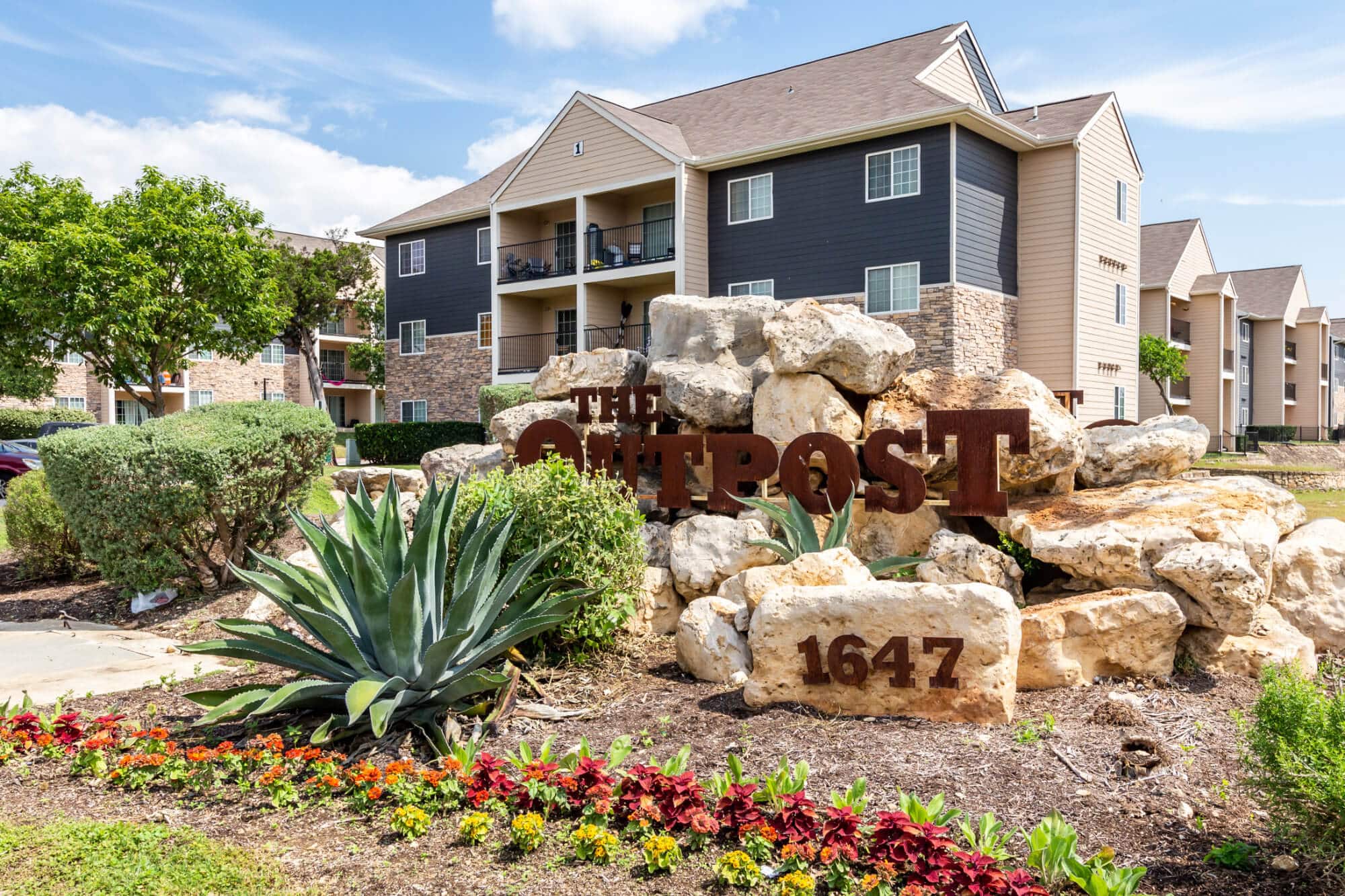 the outpost san marcos off campus apartments near texas state university monument sign with cactus and rock landscaping building exterior